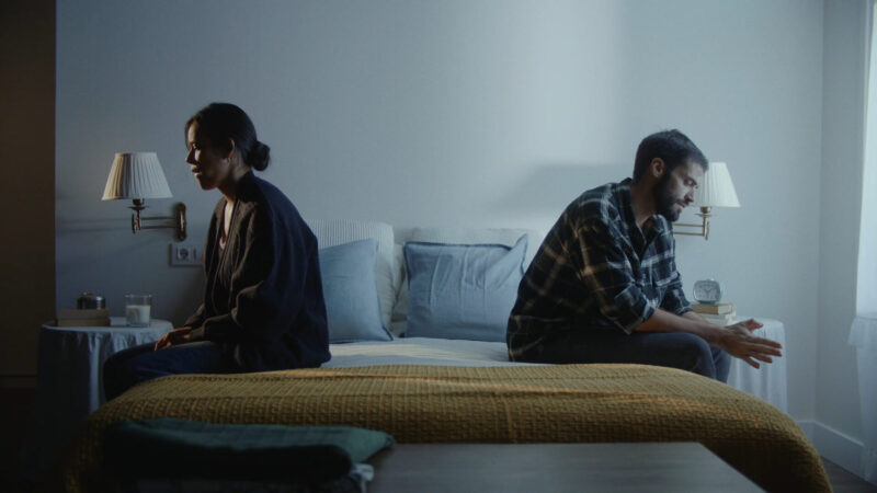 A married couple sitting on opposite sides of the bed as a sign of a toxic relationship