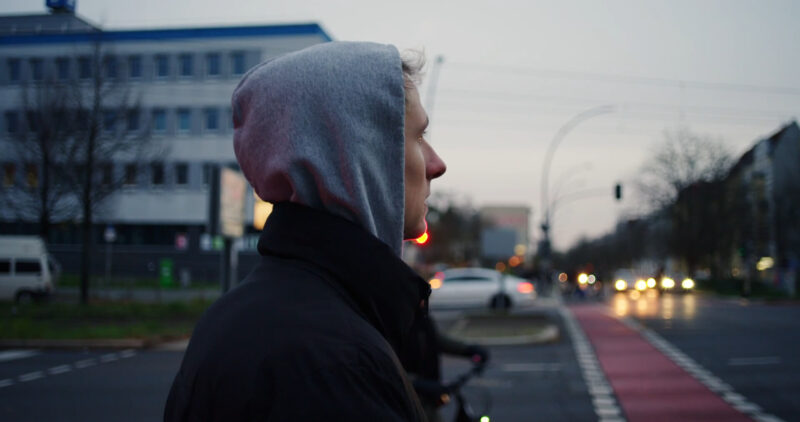 A thoughtful young man is crossing the street. The street symbolizes his life and the passing of time