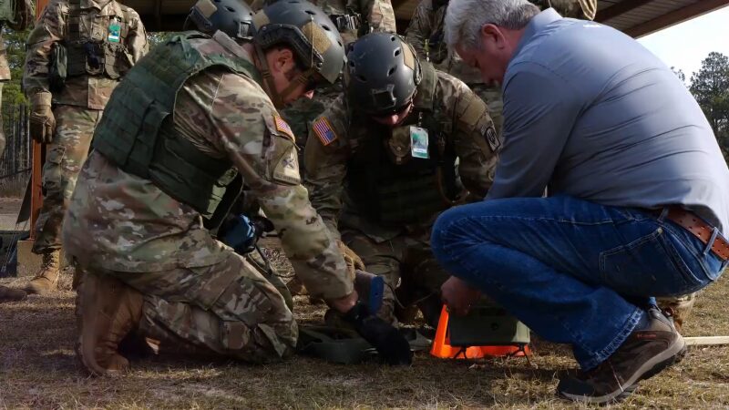 Soldiers and A Civilian Engage in A Hands-On Emergency Medical Training Session in A Field Setting, Demonstrating the Use of Realistic Live Training Systems