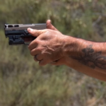 A Person Is Holding a Pistol with Both Hands in A Firm Grip During Target Practice Outdoors