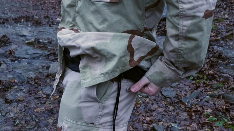 Person Adjusting a Camouflage Tactical Jacket for Better Fit and Comfort