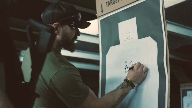 Man in Tactical Gear Marks a Target Sheet at A Gun Range