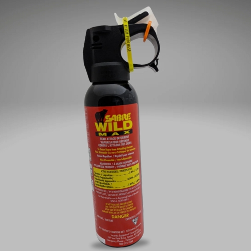 A canister of Sabre Wild Max bear spray, featuring a black nozzle and red label, set against a neutral gray background