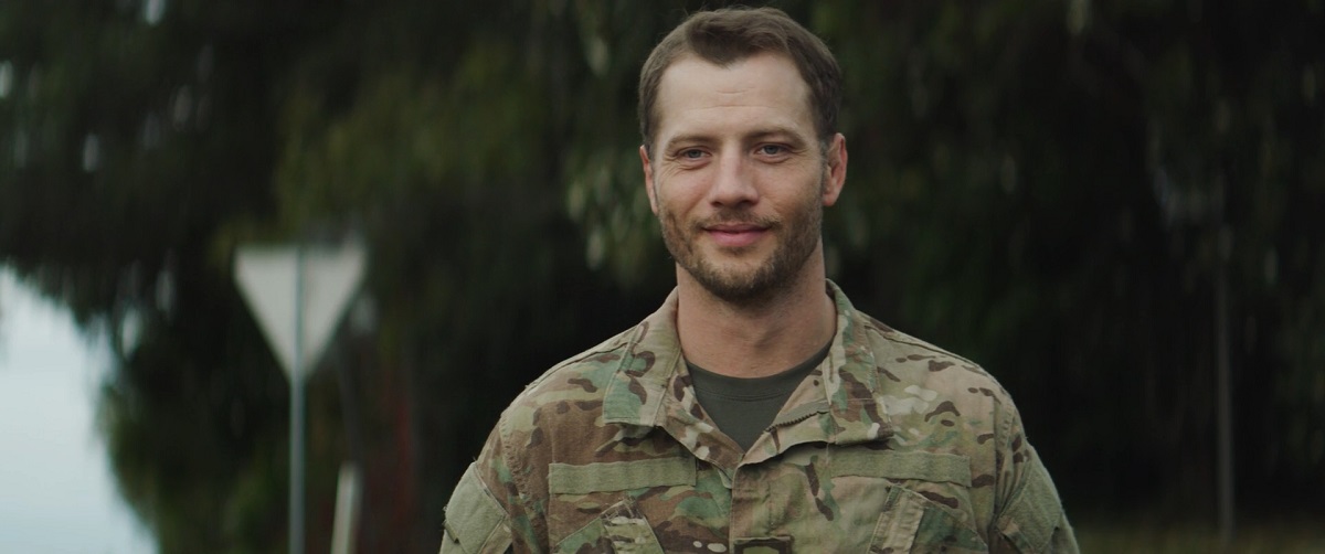 Smiling military personnel in camouflage uniform standing outdoors