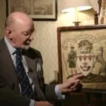 The Image Shows a Man Pointing to A Heraldic Coat of Arms, Illustrating the Concept of Ancient Symbolism in Heraldry