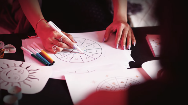 A Person Is Drawing a Personalized Spiritual Symbol, Using Colorful Markers on Paper with Zodiac Signs